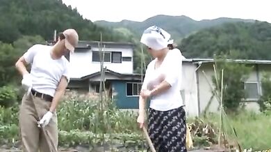Mature Japanese farmer woman bangs on the rice field outside