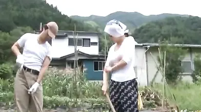 Mature Japanese farmer woman bangs on the rice field outside